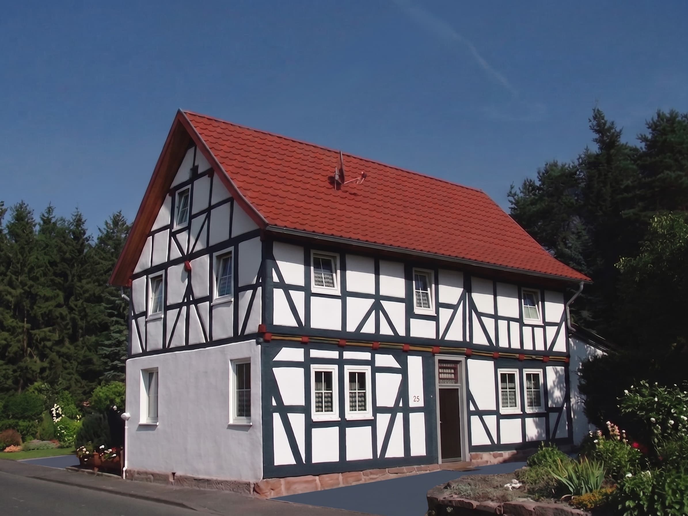 Restauriertes Fachwerkhaus mit weiß gestrichenen Gefachen und dunkelgrünem Balkenwerk